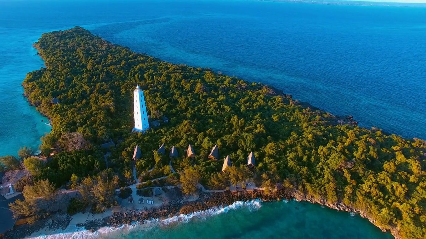 Aerial footage tracking along the Zanzibar coastline over turquoise shallows.
